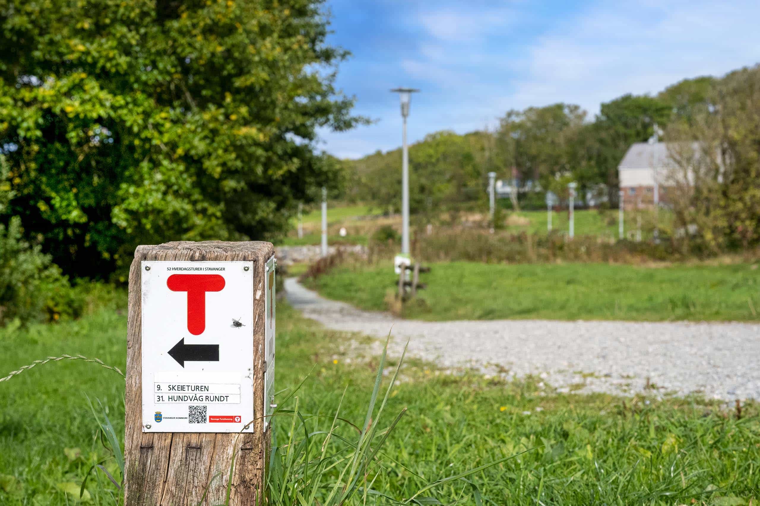 Turskilt ved en grusvei gjennom grønt landskap